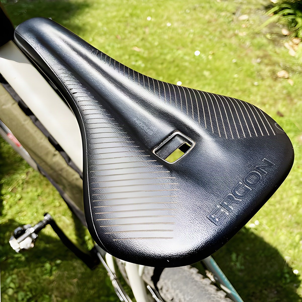 Black Ergon SR Pro saddle with its central relief channel, mounted on a gravel bike on grass.