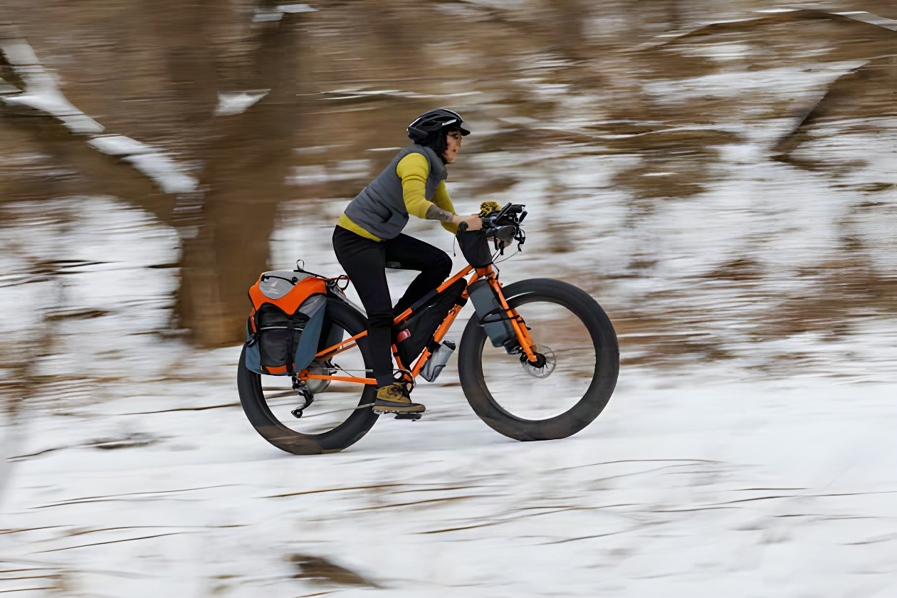 Rider on the new Surly Pugsley V2.0 fatbike with panniers speeds along a snowy trail.