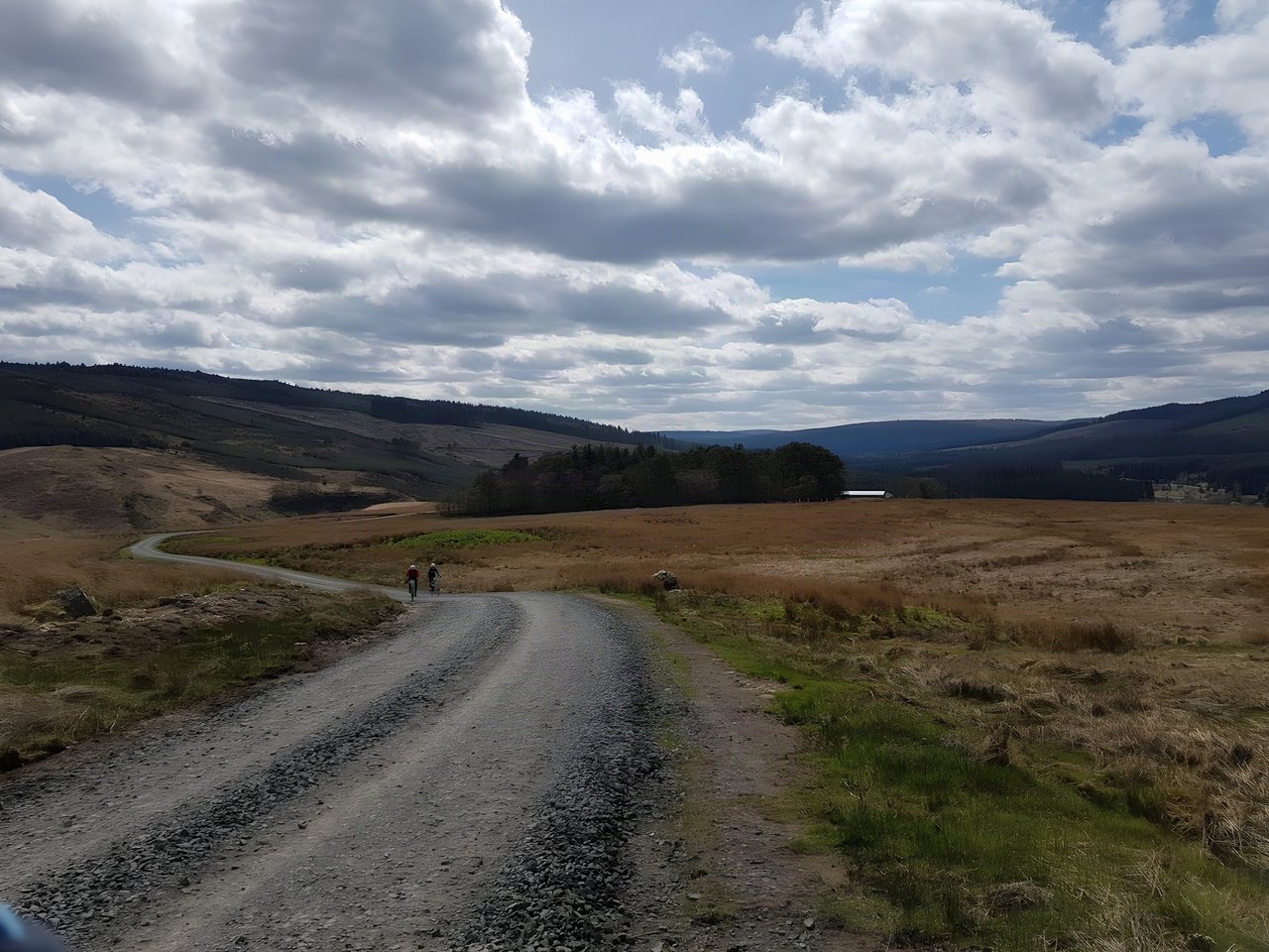 Two riders on a long gravel forest road through open moorland and hills on the Dirty Reiver 2017 near Kielder.