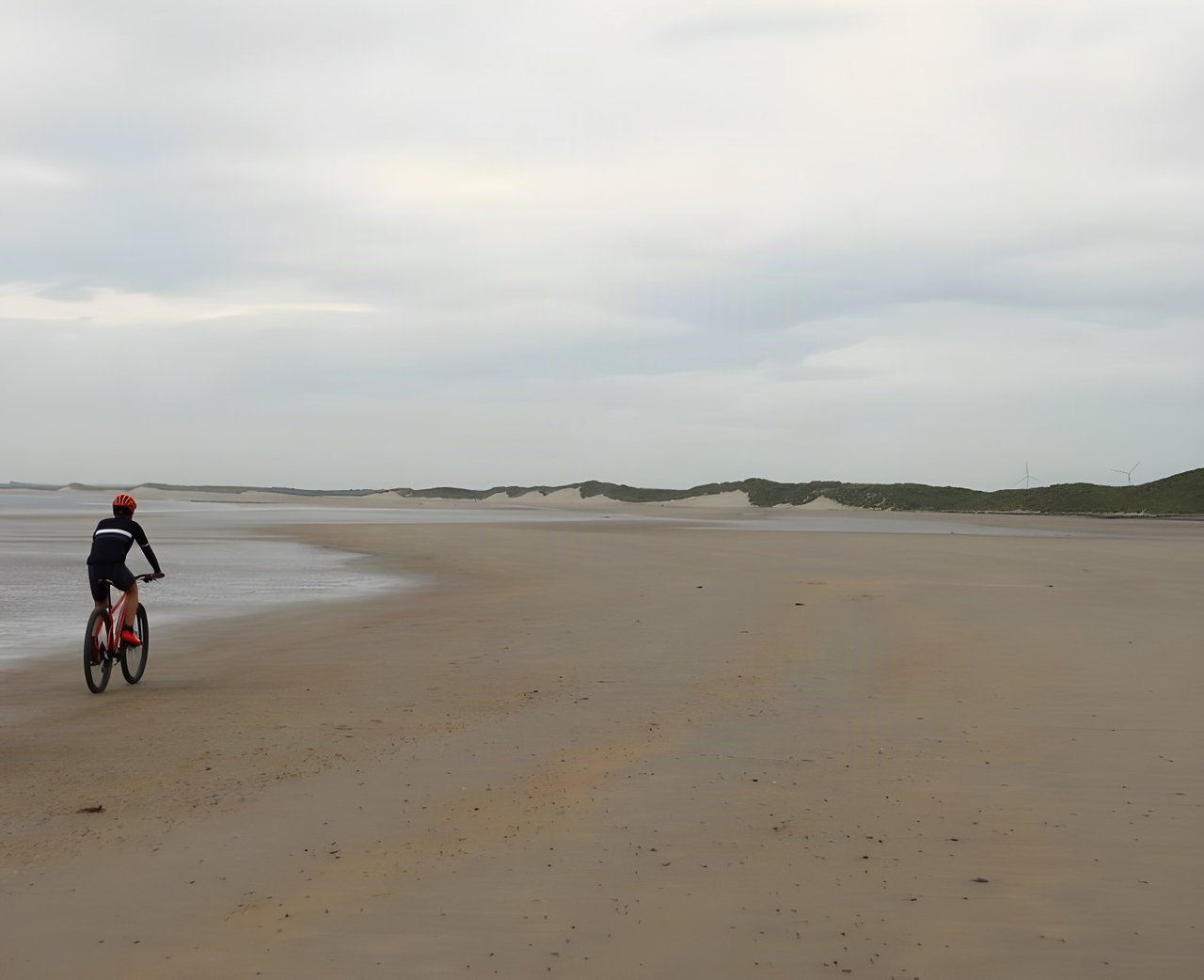 Rider cycles across the empty sands of Druridge Bay in Northumberland, venue for Sandblasted Beach Racing.