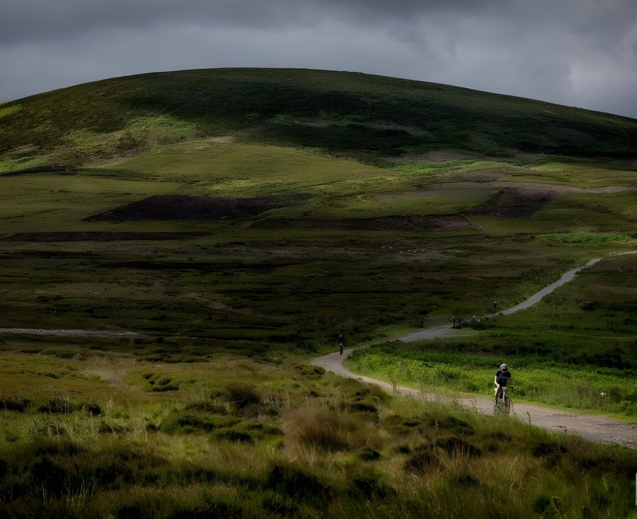 Rider on a gravel bike follows a track across green moorland during Yorkshire True Grit in the North York Moors.