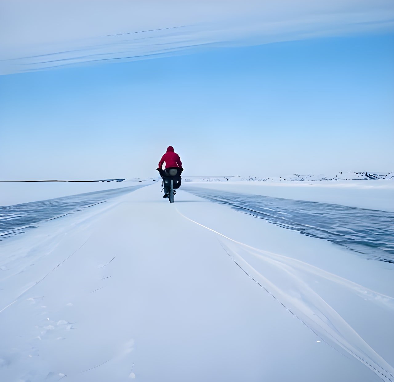 Cyclist in a red jacket rides a loaded fatbike across snow and ice, a still from The Frozen Road film in Canada's Yukon.
