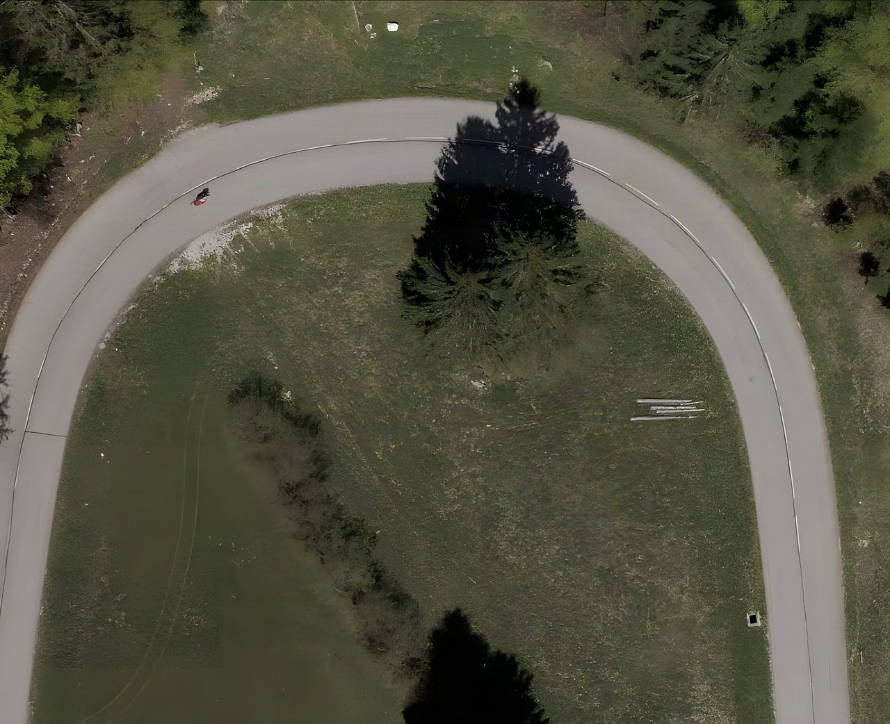 Aerial view of a lone rider on a hairpin of a quiet road, a Race Across France backdrop image.