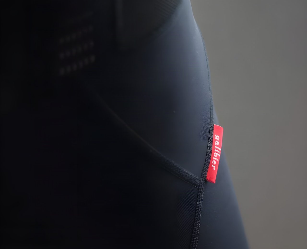 Close-up of the red Galibier label on the side seam of the black Classique Bib Shorts.