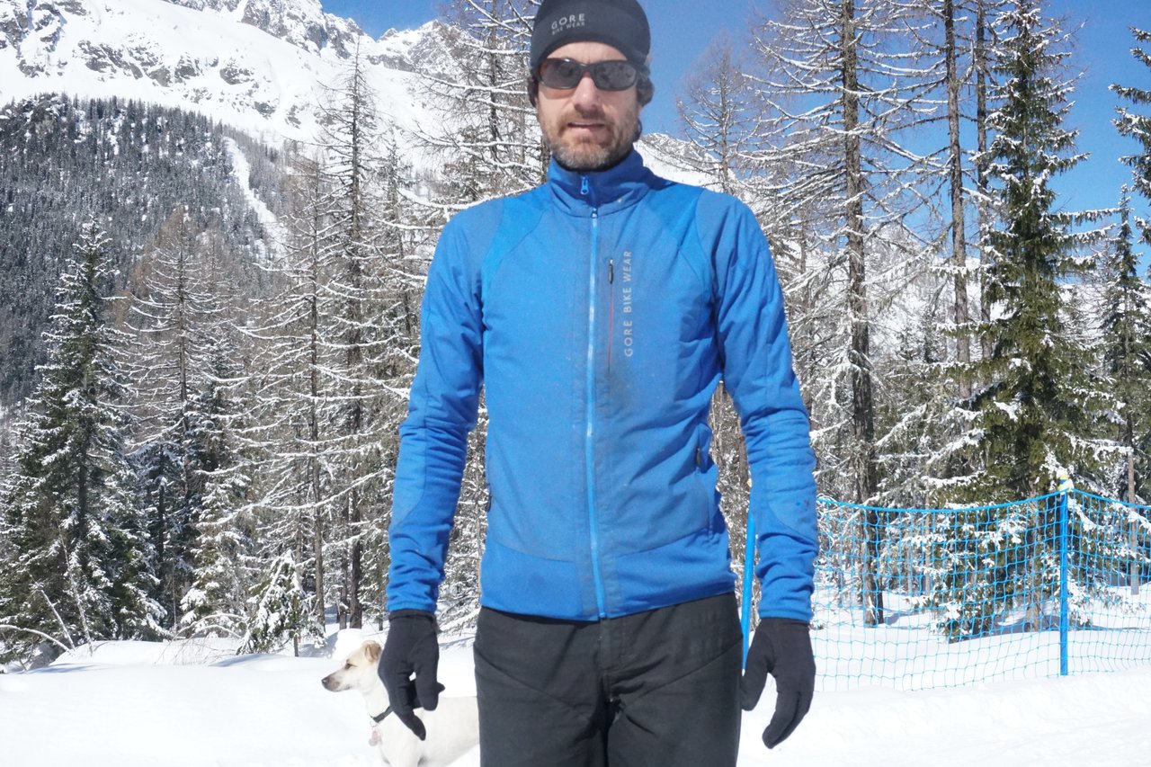Gore Wear Power Trail Primaloft jacket and The One trousers worn in snowy Alpine woodland, with a small dog.
