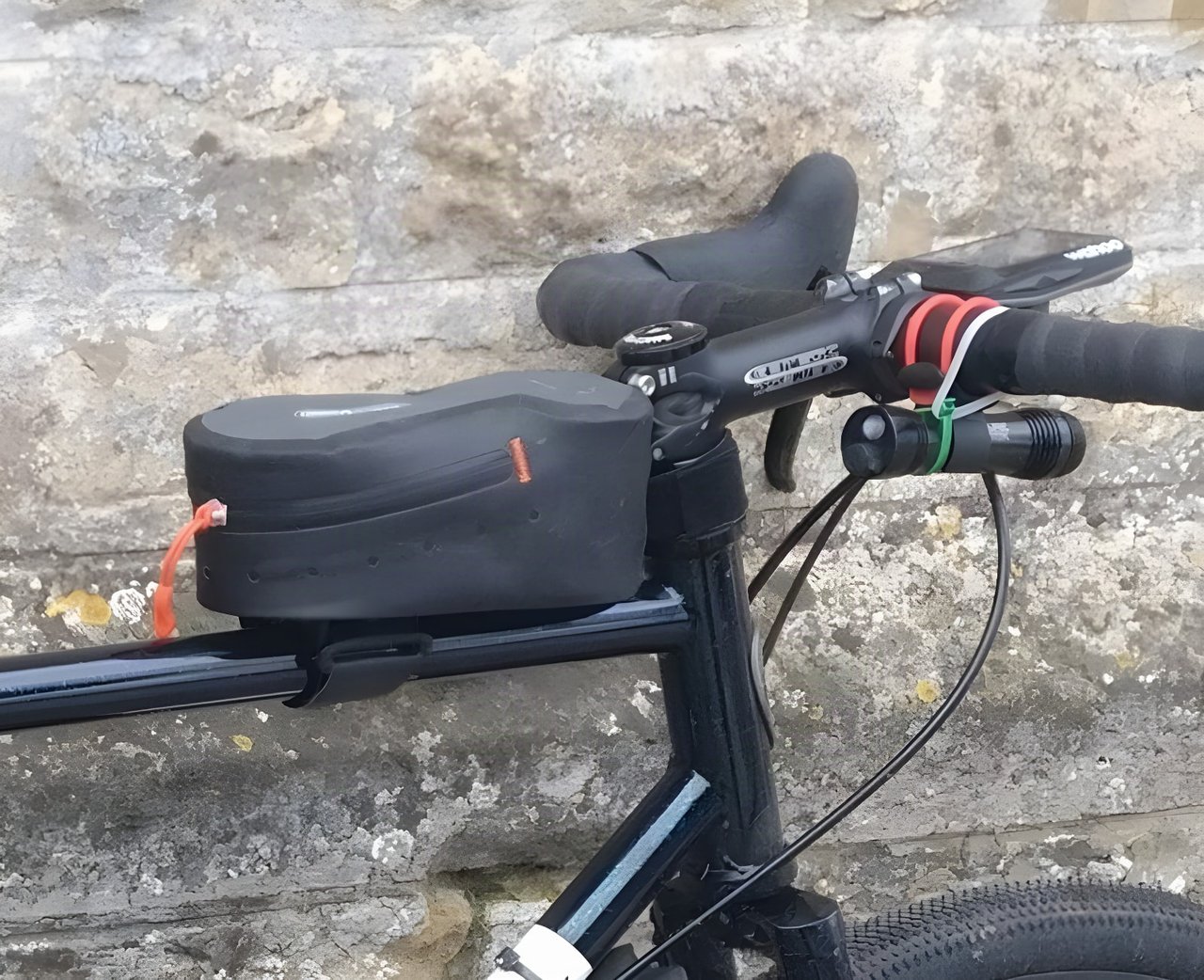Ortlieb Cockpit Pack top tube bag mounted behind the stem of a black bike, beside a handlebar light.