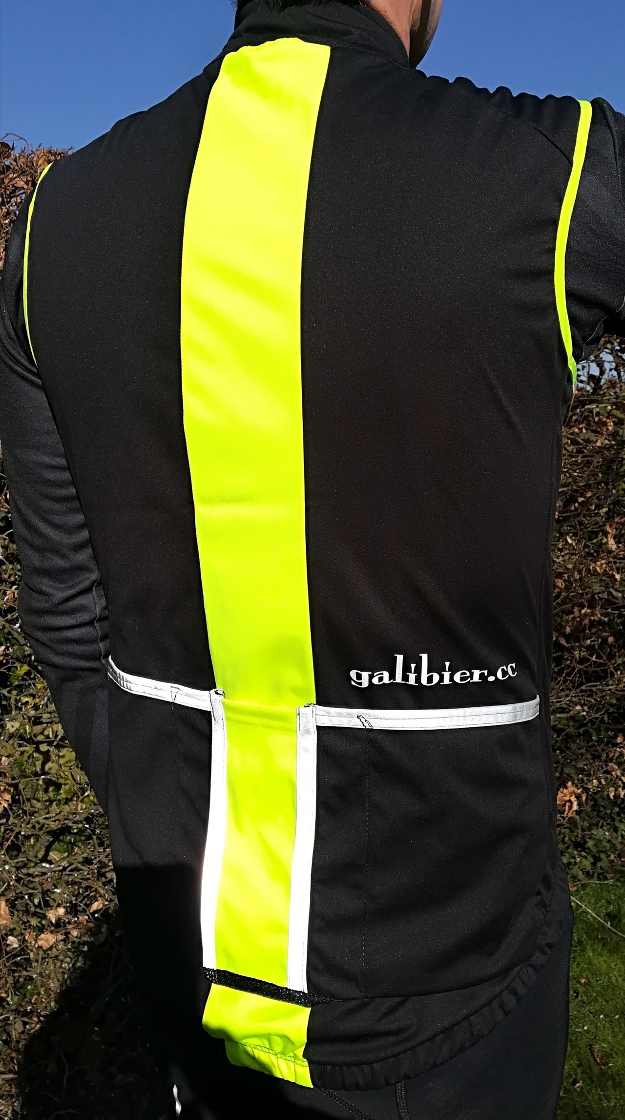 Back of the Galibier Ultimate Foul Weather Gilet in black with a fluorescent yellow centre panel and reflective pocket trim.