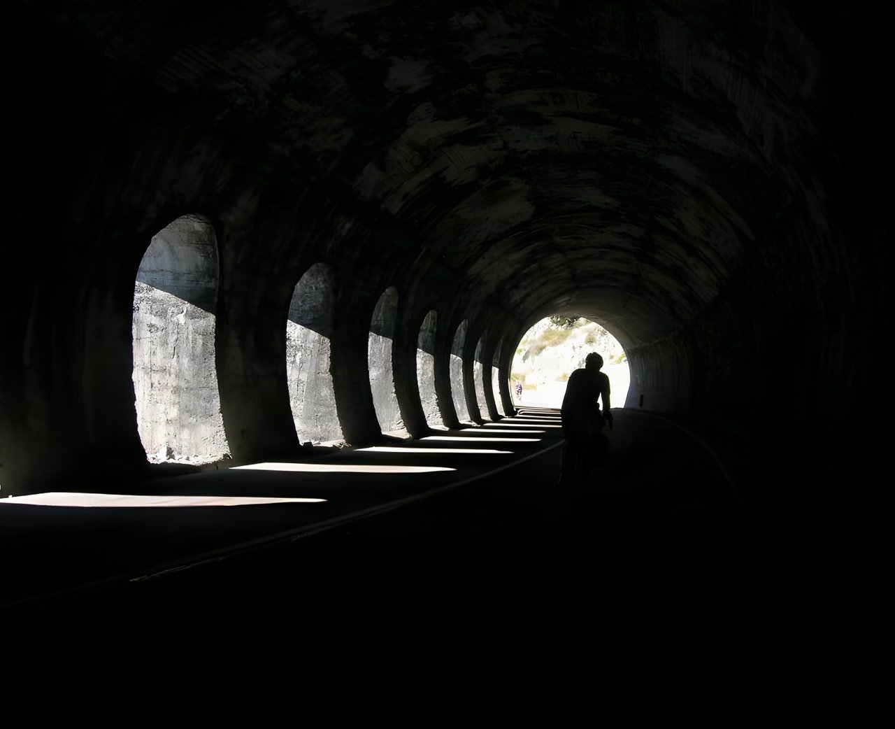 Rider silhouetted in a long arched road tunnel on the Turin Nice Rally route, the event James Olsen founded.