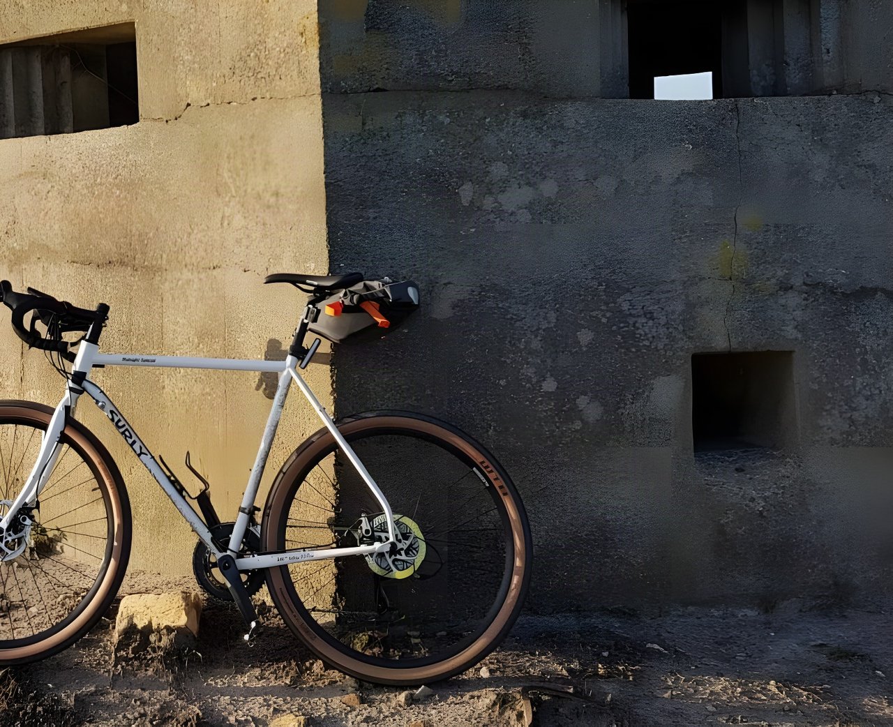 A silver Surly Midnight Special leans against a concrete pillbox.