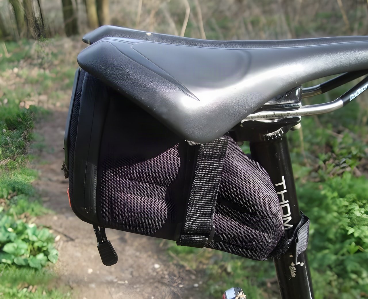Passport Frequent Flyer seat pack strapped under a saddle and to the seatpost on a woodland trail.