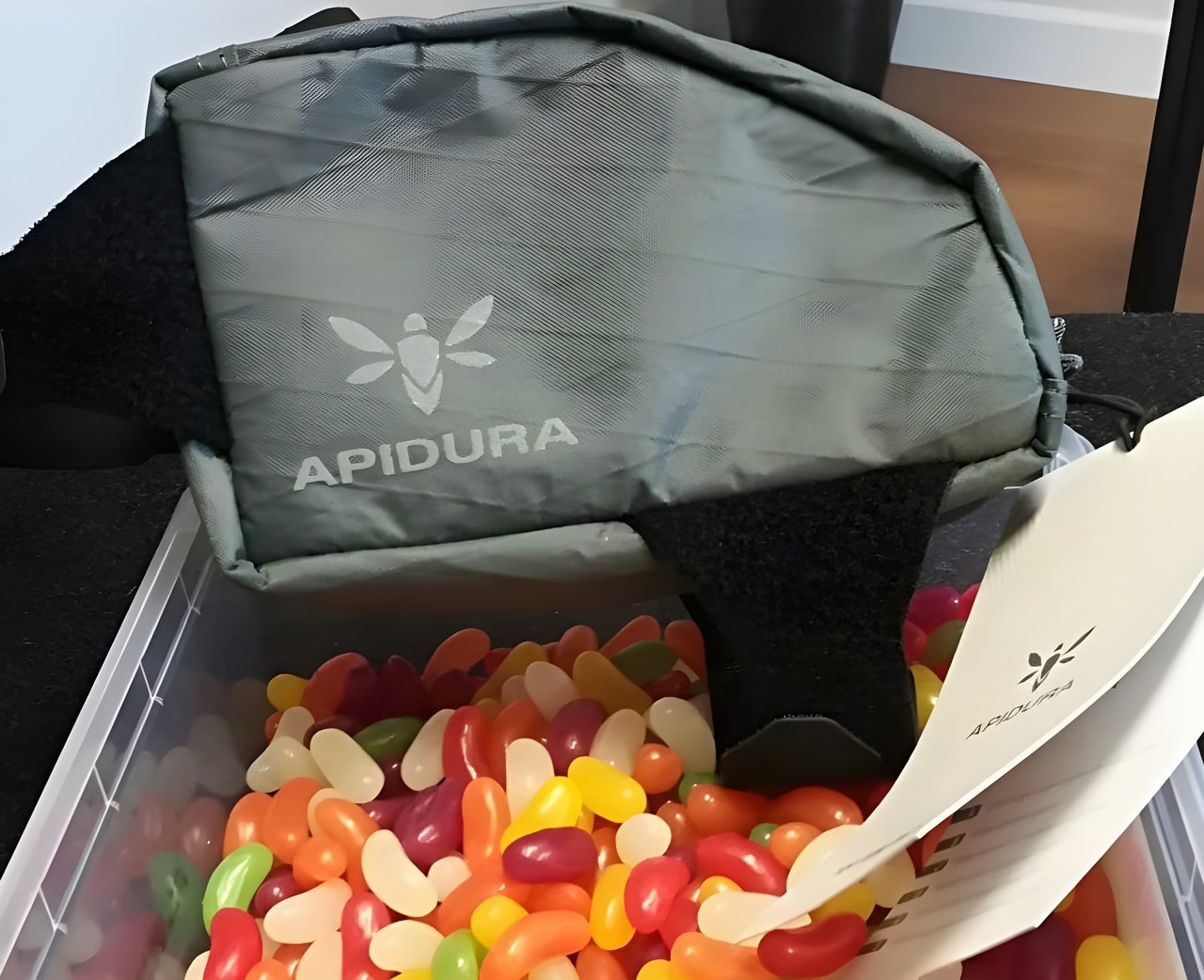 Apidura Backcountry Top Tube Bag 0.5L sitting on a tub of jelly beans, with its product tag beside it.