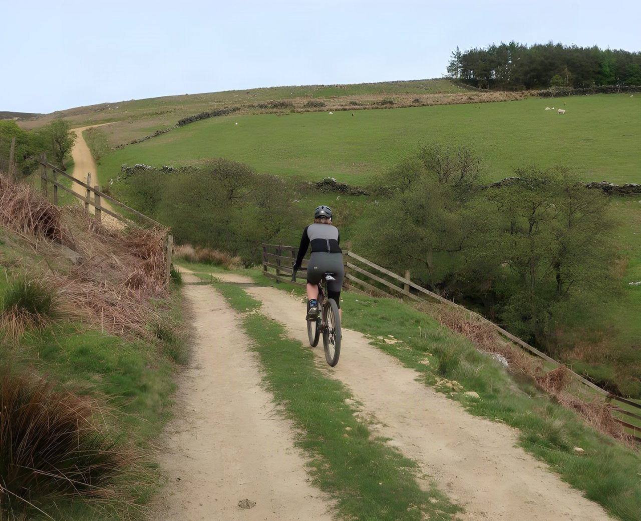 Rider on a gravel bike follows a sandy track between walled fields on the North Yorkshire Moors, Yorkshire True Grit land.