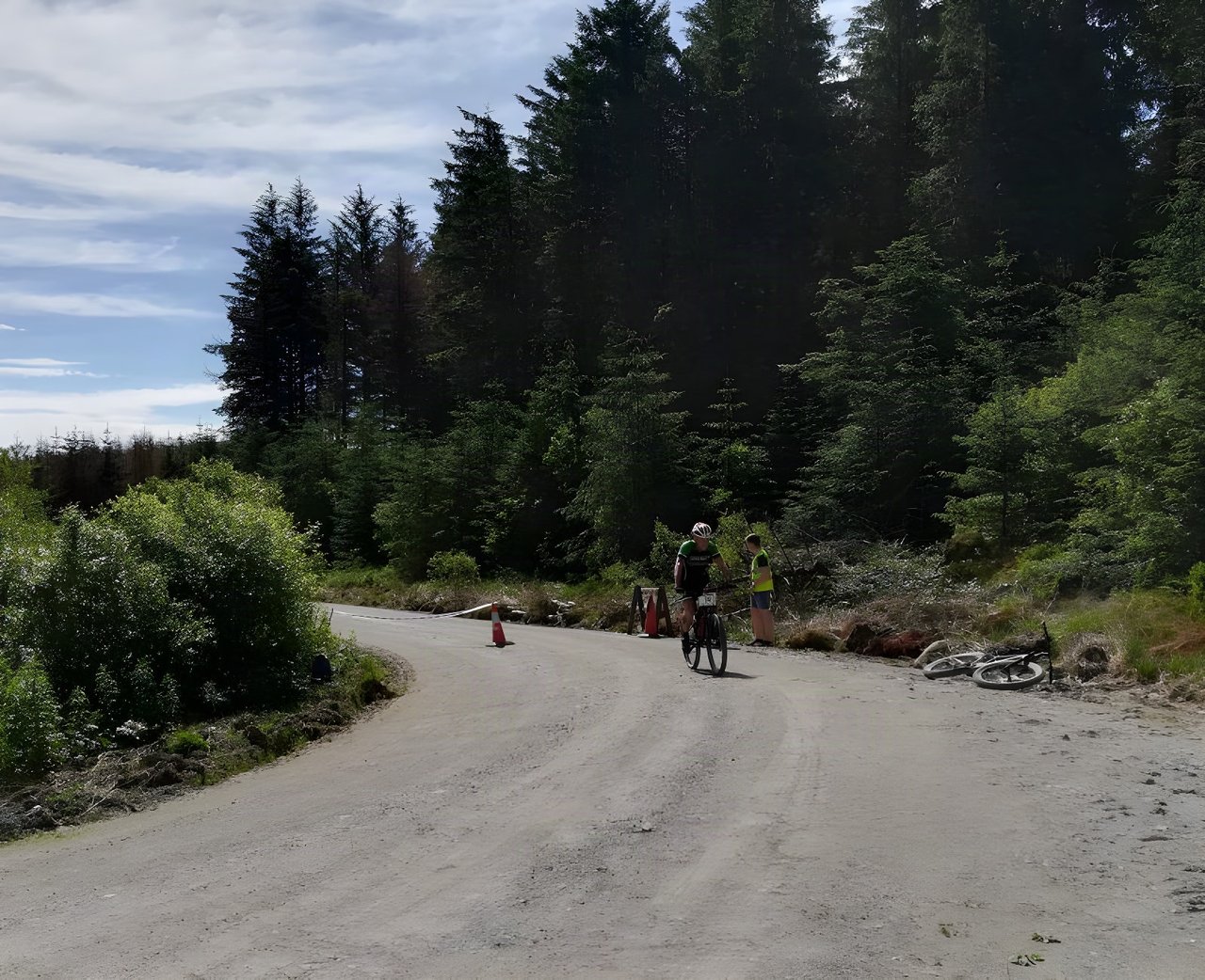 Rider passes a marshal and cones on a forest road during Gritfest 2018 near Llandovery.