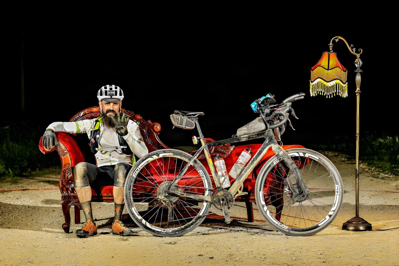 David Markman on the red chaise longue beside his dusty Salsa Warbird at night, 25 miles from the Dirty Kanza 200 finish.