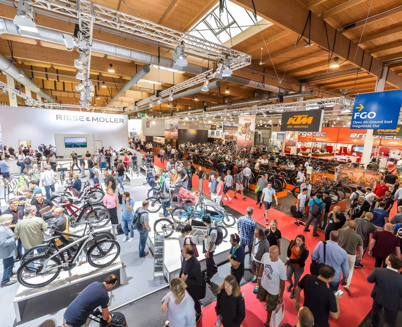 Crowded Eurobike show hall, with visitors browsing bikes between the Riese & Müller and KTM stands.