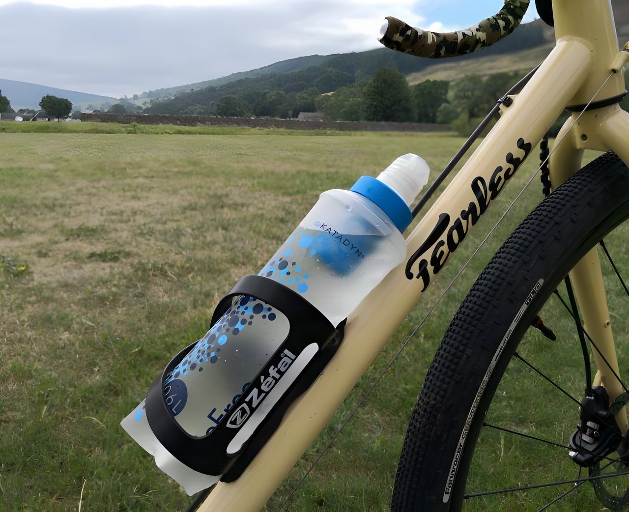 Katadyn BeFree soft flask filter bottle mounted in a Zéfal cage on a cream Fearless gravel bike, hills behind.