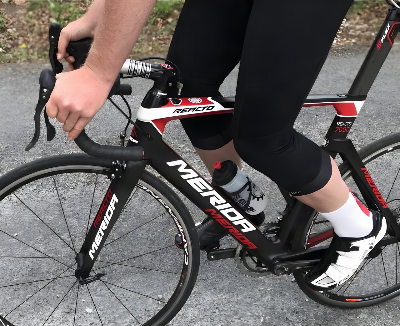 Rider's legs in Galibier 3/4 Peloton Bib Knickers, ending below the knee, on a Merida Reacto road bike.