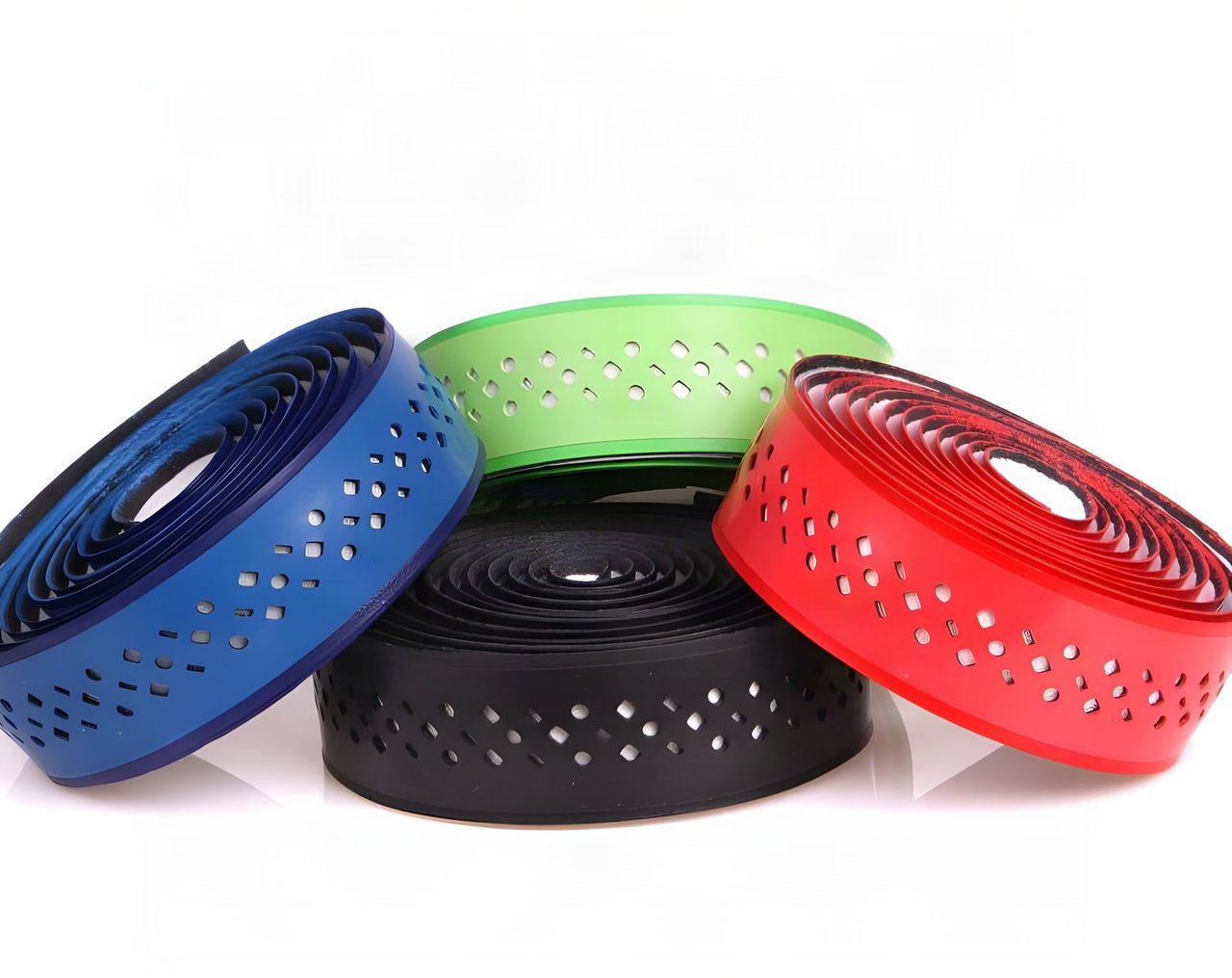 Four rolls of perforated ODI 3.5mm Performance Bar Tape in blue, green, red and black, stacked on white.