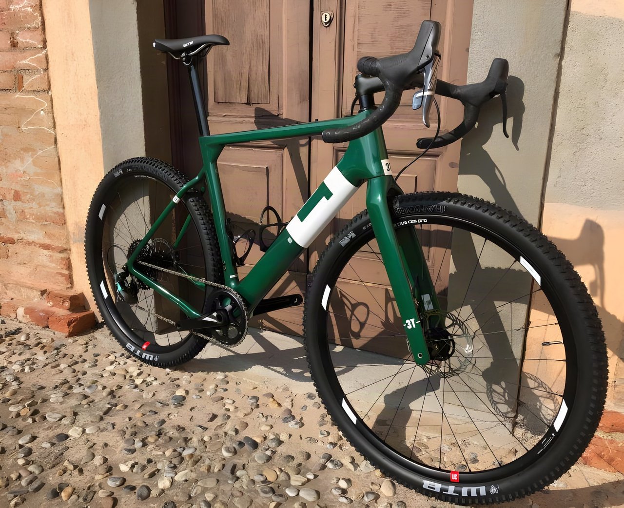 Limited edition Team Force Green 3T Exploro Flatmount gravel bike leaning against a wooden door.
