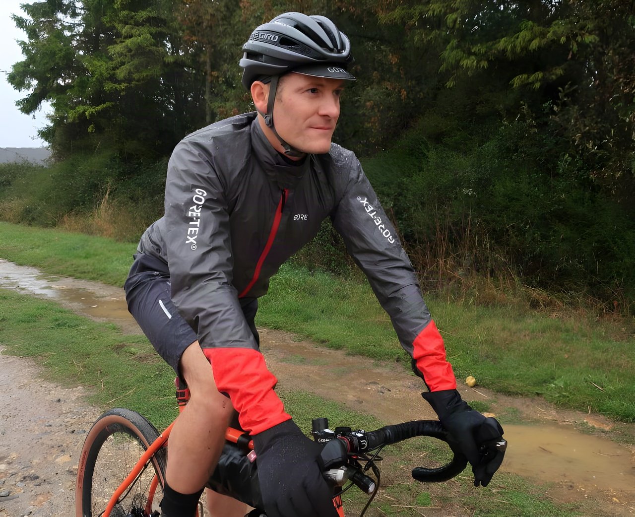 Rider in the Gore C5 Gore-Tex Shakedry 1985 Viz jacket on a wet gravel track, red cuffs and logos visible.