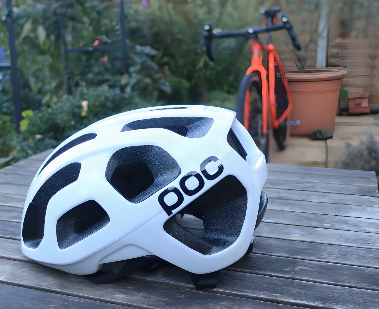 White POC Octal helmet on a garden table, with an orange drop-bar bike behind.