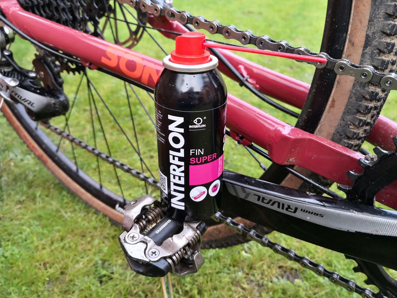 A can of Interflon Fin Super lube resting on a bike's chainstay and pedal