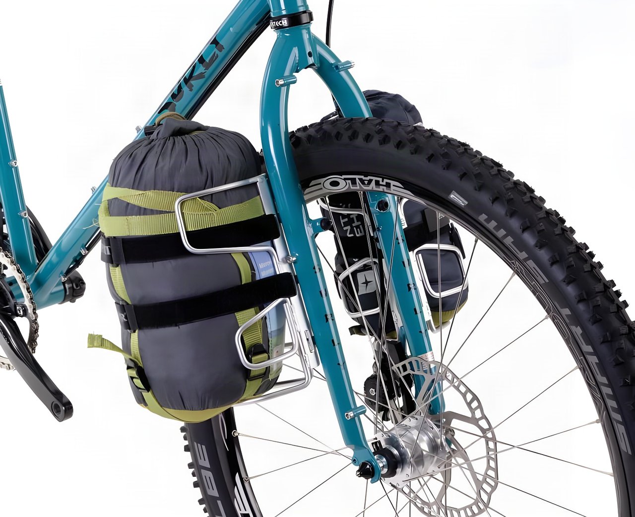 Pair of silver Passport Cycles Lug-Kages on a teal Surly fork, each holding a stuff sack, on a white background.