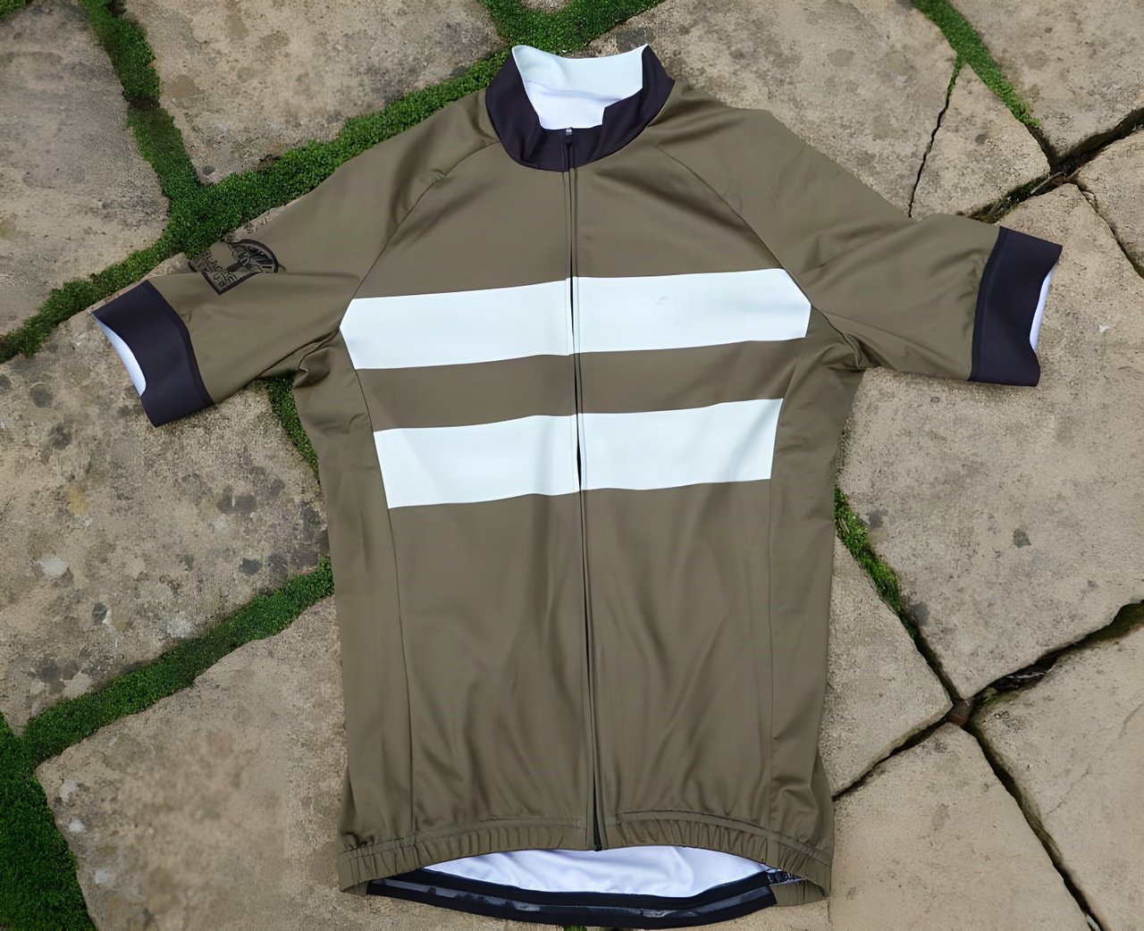 Blackmore Cycling Apparel Cadet jersey in olive green with two pale stripes, laid flat on paving.