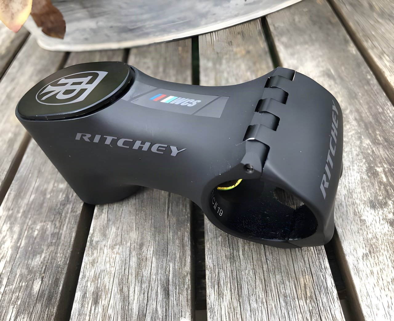 Ritchey WCS Chicane stem in matt black with magnetic top cap and hinged faceplate, resting on a wooden bench.