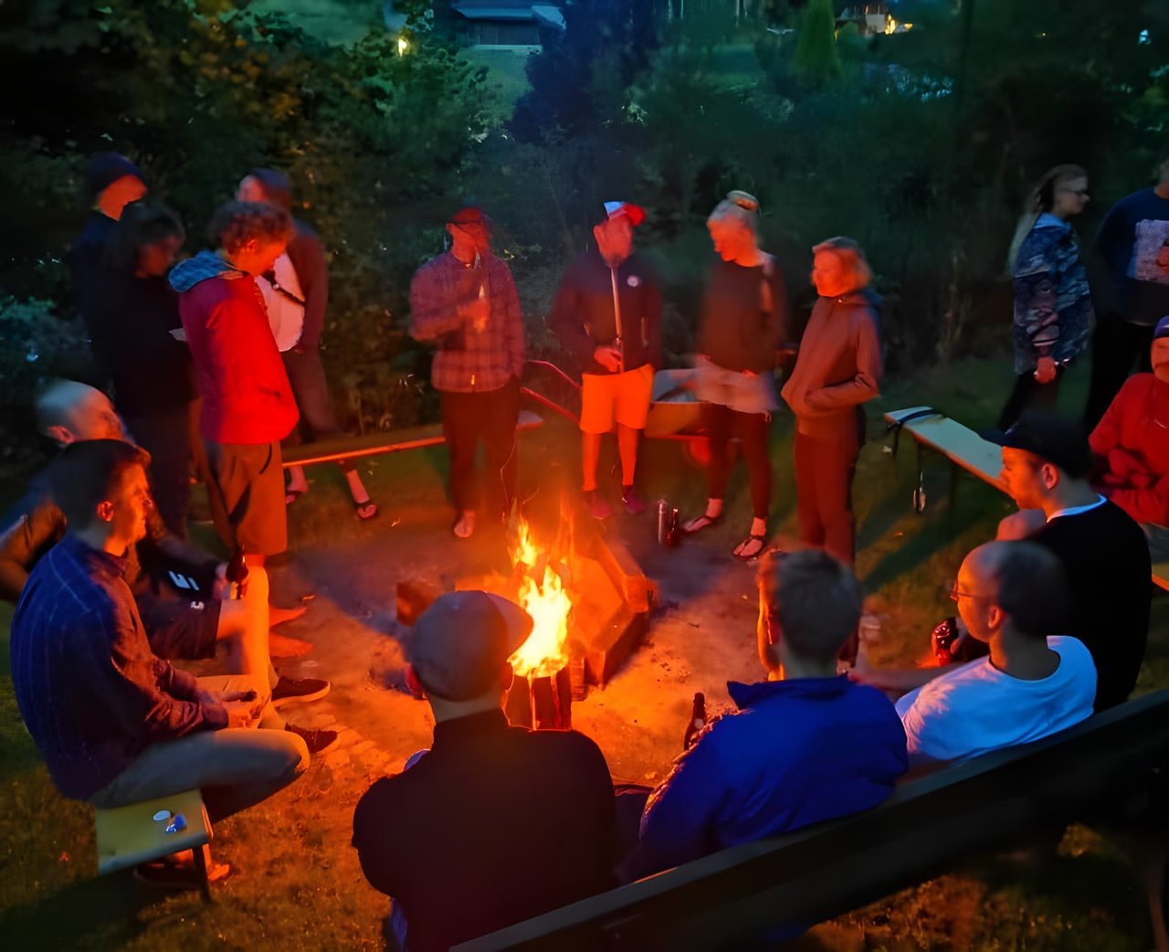 Riders and guests gather around a campfire at dusk during Bombtrack's Groundwork event near Cologne.