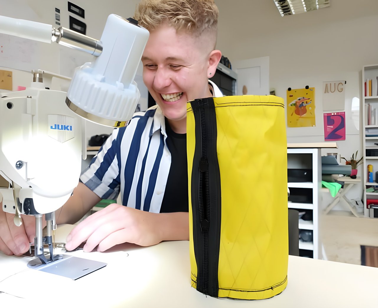 Straight Cut founder Ross O'Reilly laughs at his sewing machine beside a finished yellow bikepacking bag.