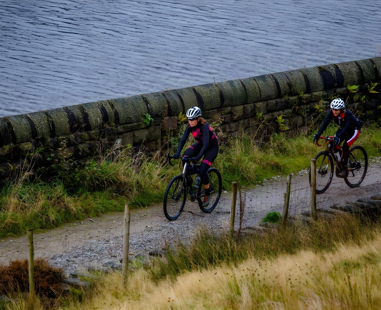 Emma Osenton leads a second rider along a gravel track beside a reservoir on the PennDURO, on her Kinesis Tripster V3.