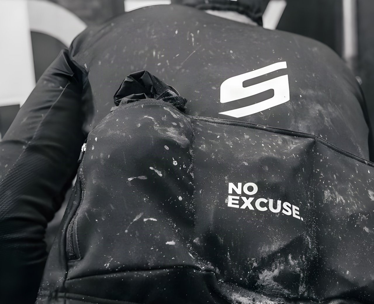 Mud-spattered rider's back with a Scope logo and "No Excuse" slogan at the Backyard Breakaway gravel ride.
