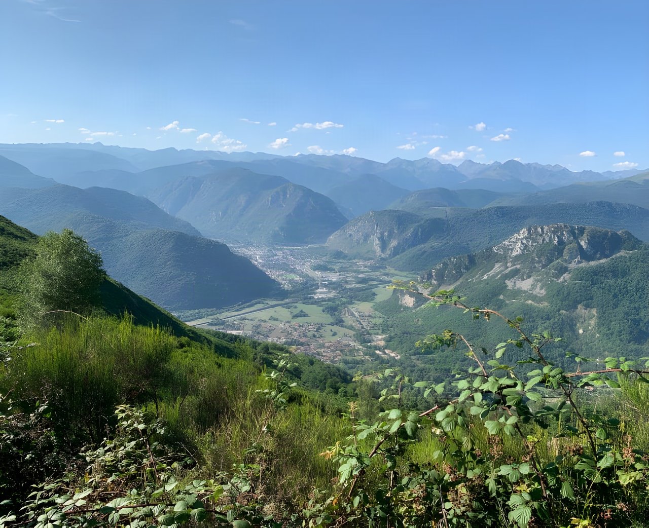 View down a green Pyrenees valley from a hillside on the Further bikepacking race in France.