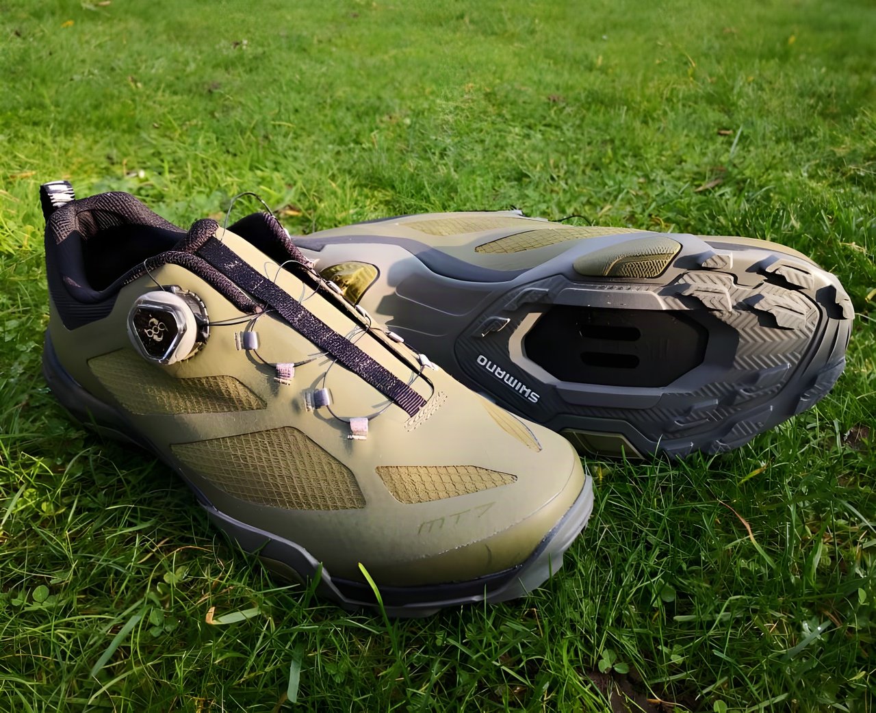 Shimano MT-7 SPD shoes in olive green with a BOA dial, one shown upright and one on its side to show the sole.