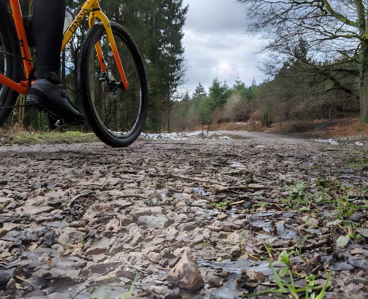 Low view of an orange Genesis gravel bike on a stony Forest of Dean track, where the Dirty Devil series is ridden.