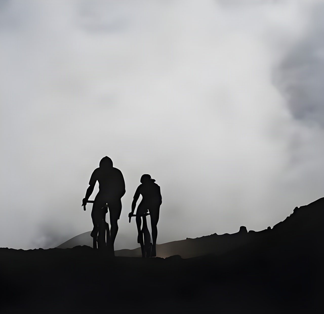 Two riders in silhouette climb a ridge into low cloud on Maui, Hawaii, from Kona's Into the Clouds film.