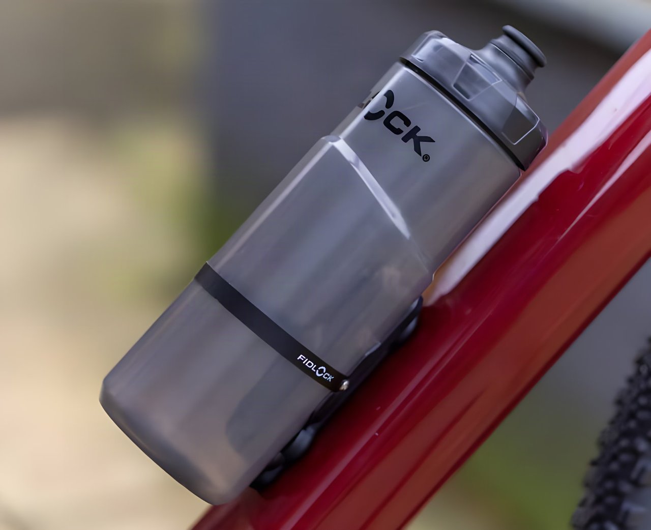 Fidlock TWIST 600 bottle held magnetically on the down tube of a red bike frame.