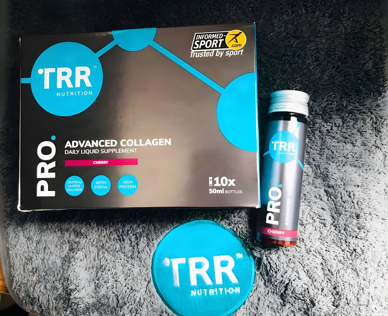 TRR Nutrition Pro Advanced Collagen box and a 50ml cherry bottle on a grey fleece.