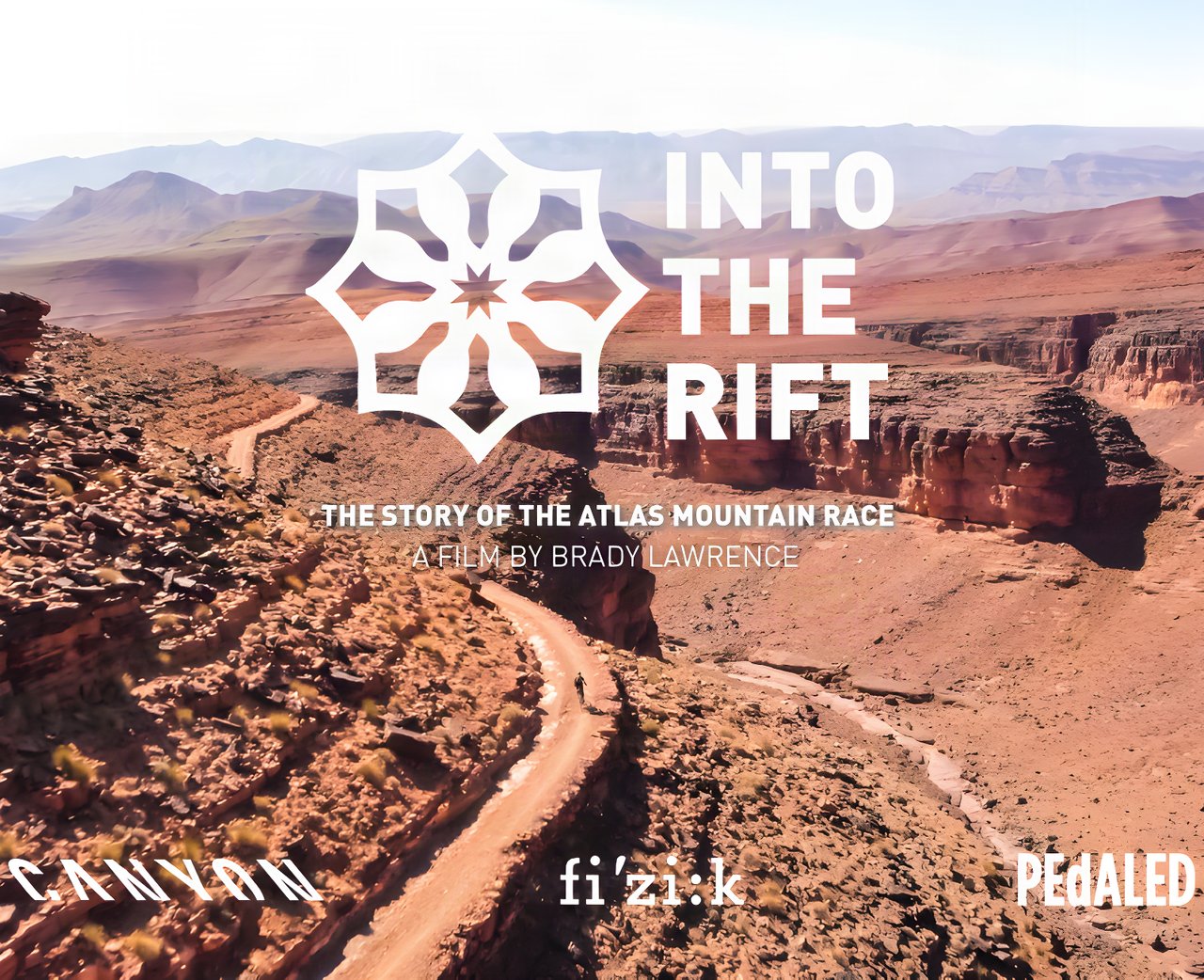 Into the Rift title card for the Atlas Mountain Race film, over a Moroccan canyon track with sponsor logos.