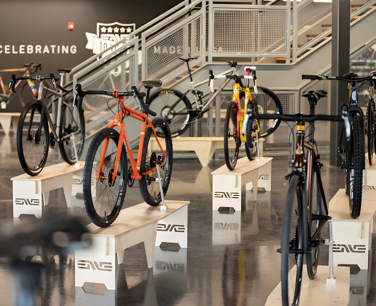 Custom gravel bikes on plywood ENVE stands at the Builder Round-Up 2020, with an orange steel bike at the front.