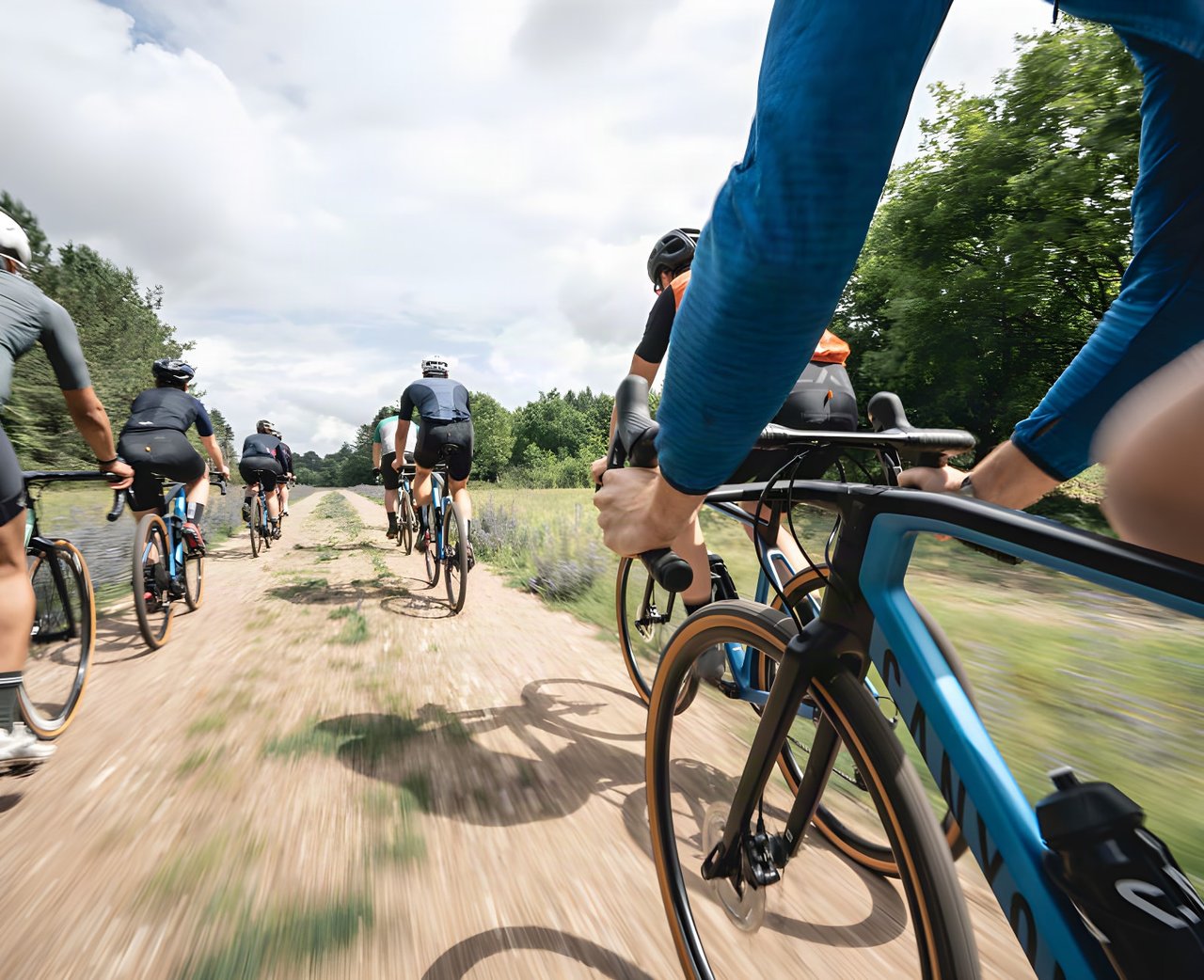 Group of riders on a dusty gravel track, a Canyon bike in the foreground, promoting the Grinduro Wales giveaway.