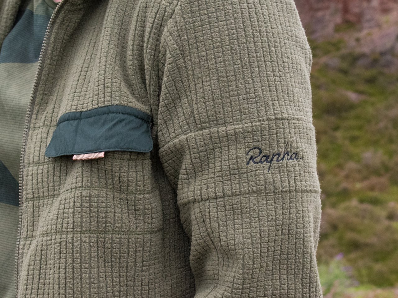 Rapha Explore Technical Hoodie in olive grid fleece, close-up of the sleeve logo and chest pocket, from the range on test.