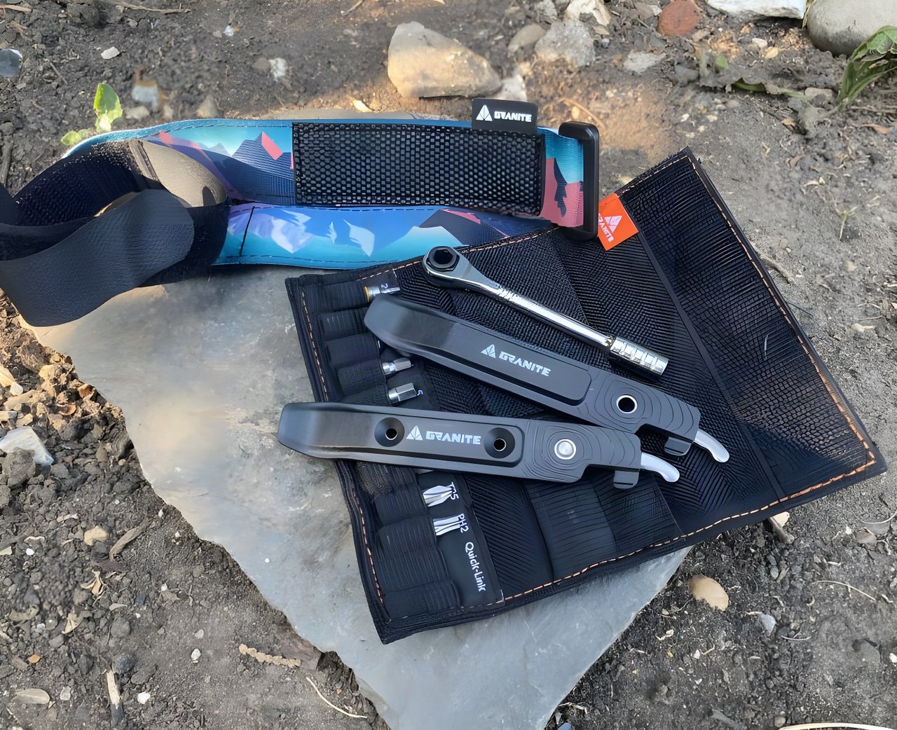 Granite Design ROCKnROLL tool roll, TALON tyre levers and ROCKBAND+ strap laid out on a flat stone.