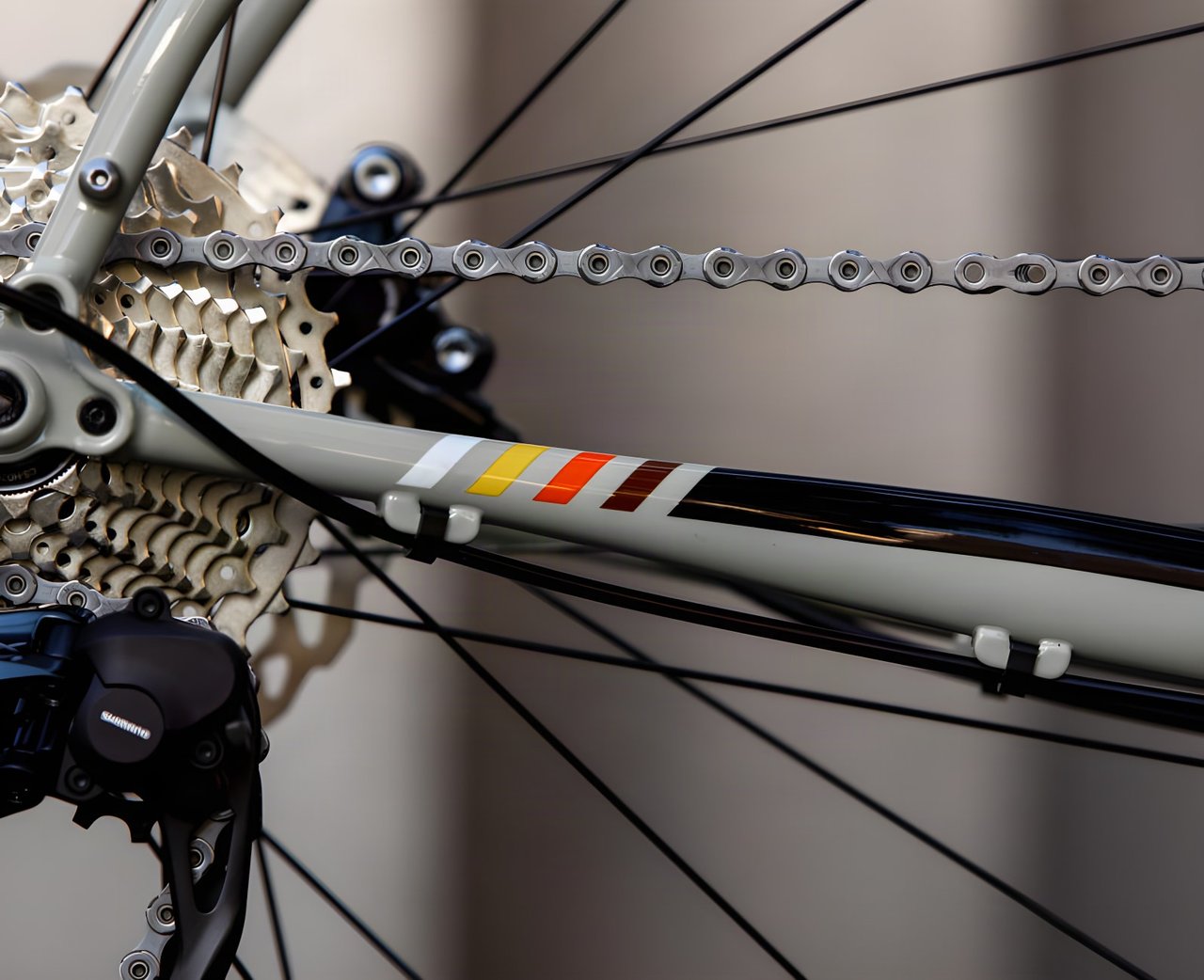 Close-up of the 2021 Bombtrack Audax chainstay in sage green with its stripe decal, cassette and Shimano rear mech.