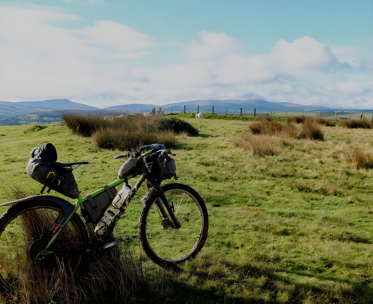 Chris Lansley's loaded Cotic bikepacking bike leans in tussocky grass below Brecon Beacons hills on the Bear Bones 200.
