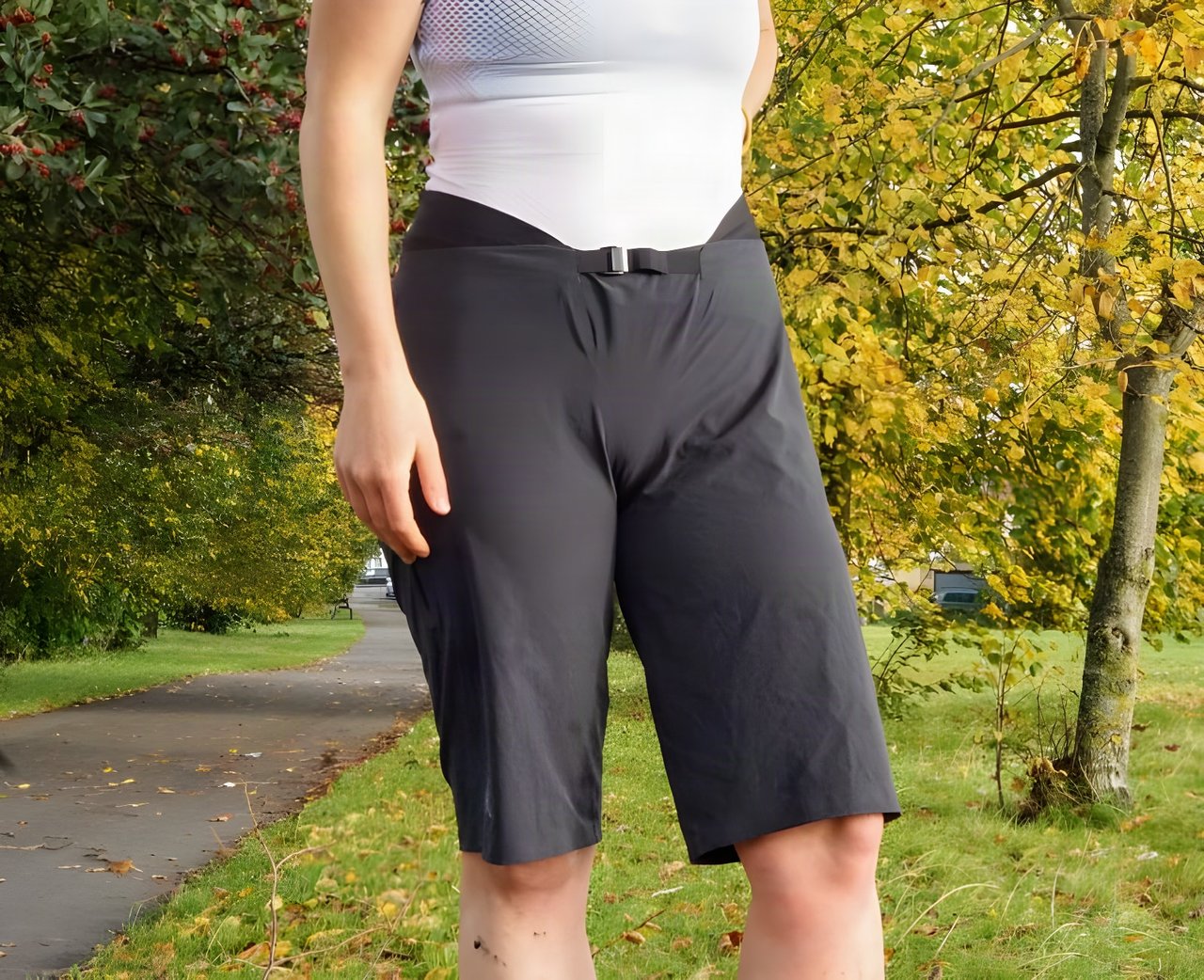 7mesh Slab baggy shorts in slate grey with a webbing buckle waist, worn on a park path in autumn.