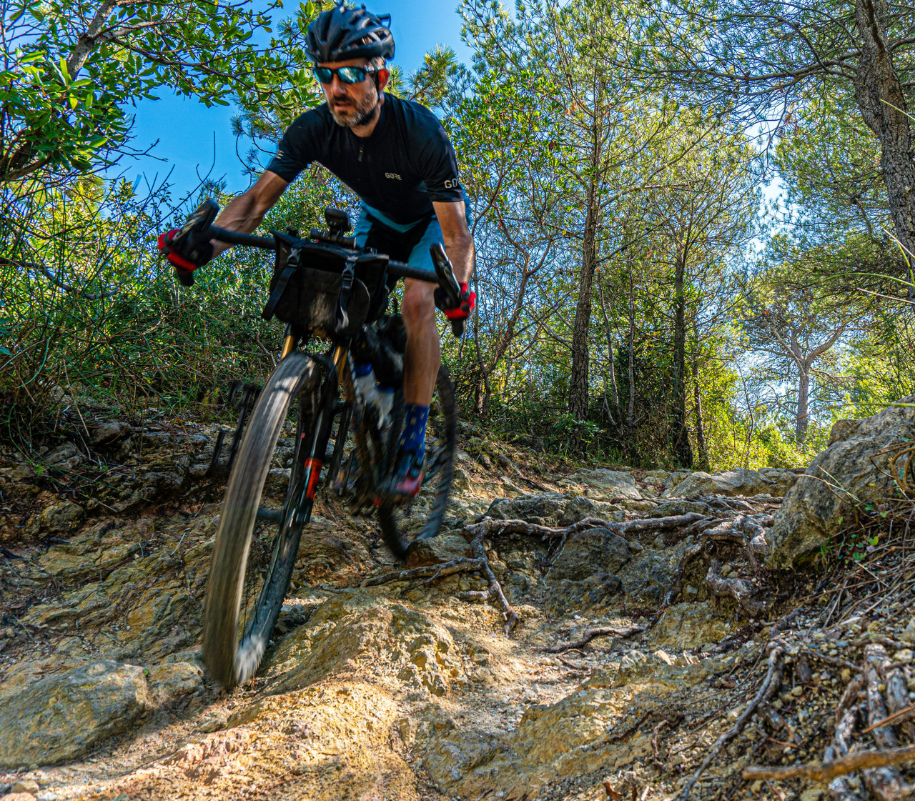 Rider on a loaded drop-bar bike fitted with Curve Walmer 55cm handlebars descends a rocky wooded trail.