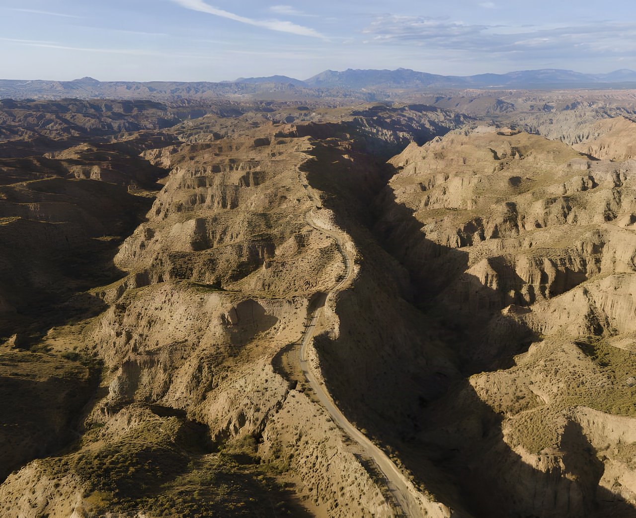 Aerial view of a gravel road winding through the eroded badlands of the Gorafe Desert, Badlands race route in Spain.