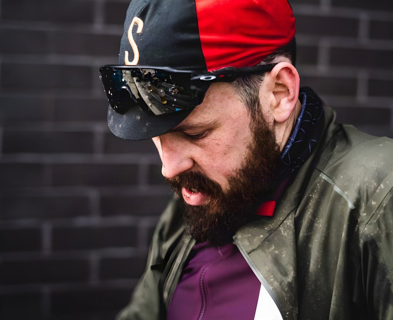 Photographer Dan Monaghan in a cycling cap and sunglasses looks down in a close portrait for the AUTMNL ADVNTR interview.